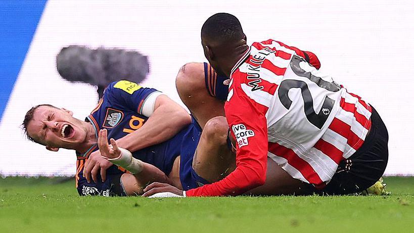 Dan Burn holds his rib after a tackle from Nordi Mukiele during Newcastle United's game against Sunderland at the Stadium of Light on 14 December, 2025