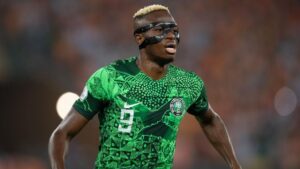 Victor Osimhen wearing the Nigerian green jersey and a black mask on his face looks sideways during a 2023 Afcon match