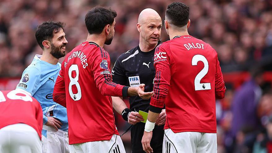 Diogo Dalot of Manchester United receives a yellow card from referee Anthony Taylor